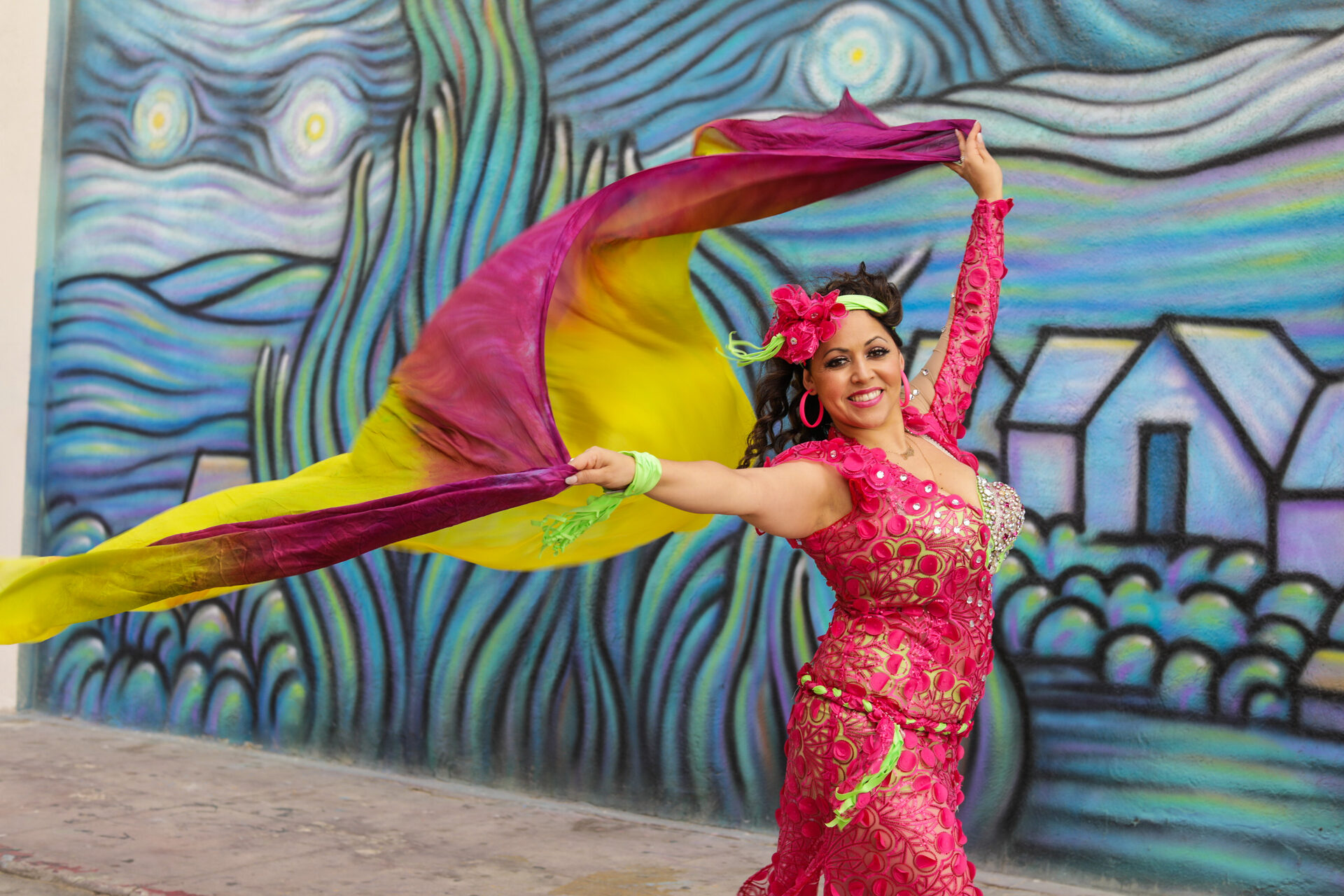 Dancer performing a veil routine in front of a colourful mural