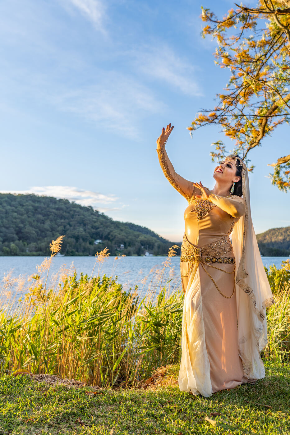 Jrisi performing a solo Persian dance by the water in gold costume